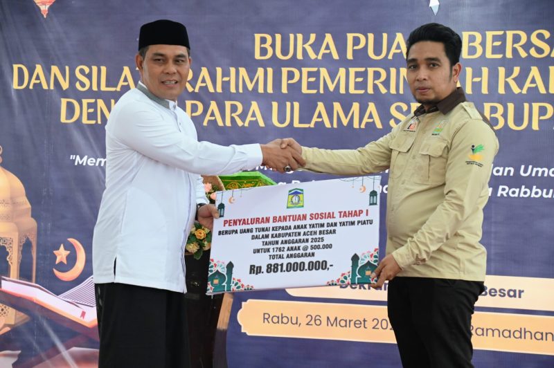 Bupati Aceh Besar H Syech Muharram Idris menyerahkan penyaluran bantuan sosial tahap I berupa uang tunai kepada anak yatim piatu yang terima langsung oleh Plt Kadinsos Aceh Besar Aulia Rahman SSTP MSi, dalam acara buka puasa bersama dan silaturrahmi Pemkab Aceh Besar bersama Ulama Kab. Aceh Besar, Rabu (26/03/2025).