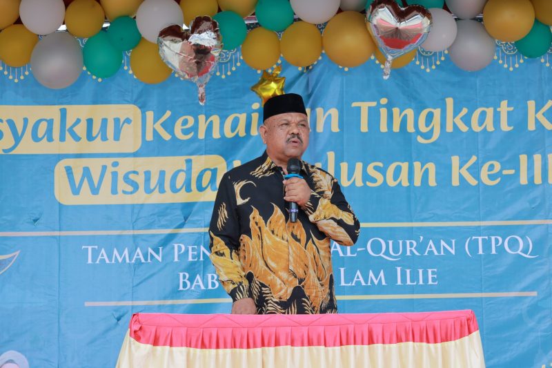 Kepala Dinas Syariat Islam Aceh Besar Rusdi S.Sos MSi menyampaikan sambutan pada Tasyakkur Kenaikan Tingkat IV dan Wisuda III TPQ Baburridha di halaman Mesjid Lam Ilie, Indrapuri, Minggu (22/06/2025). 
