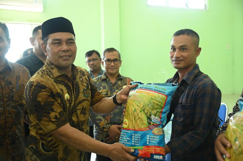Bupati Aceh Besar H Muharram Idris didampingi Kepala Dinas Pertanian Aceh Besar Jakfar. SP, MSi menyerahkan bibit padi gogo jenis inpari 32 HDB kepada petani di 11 kecamatan di Aceh Besar, di Aula BPP Kuta Malaka, Kamis (26/06/2025). 