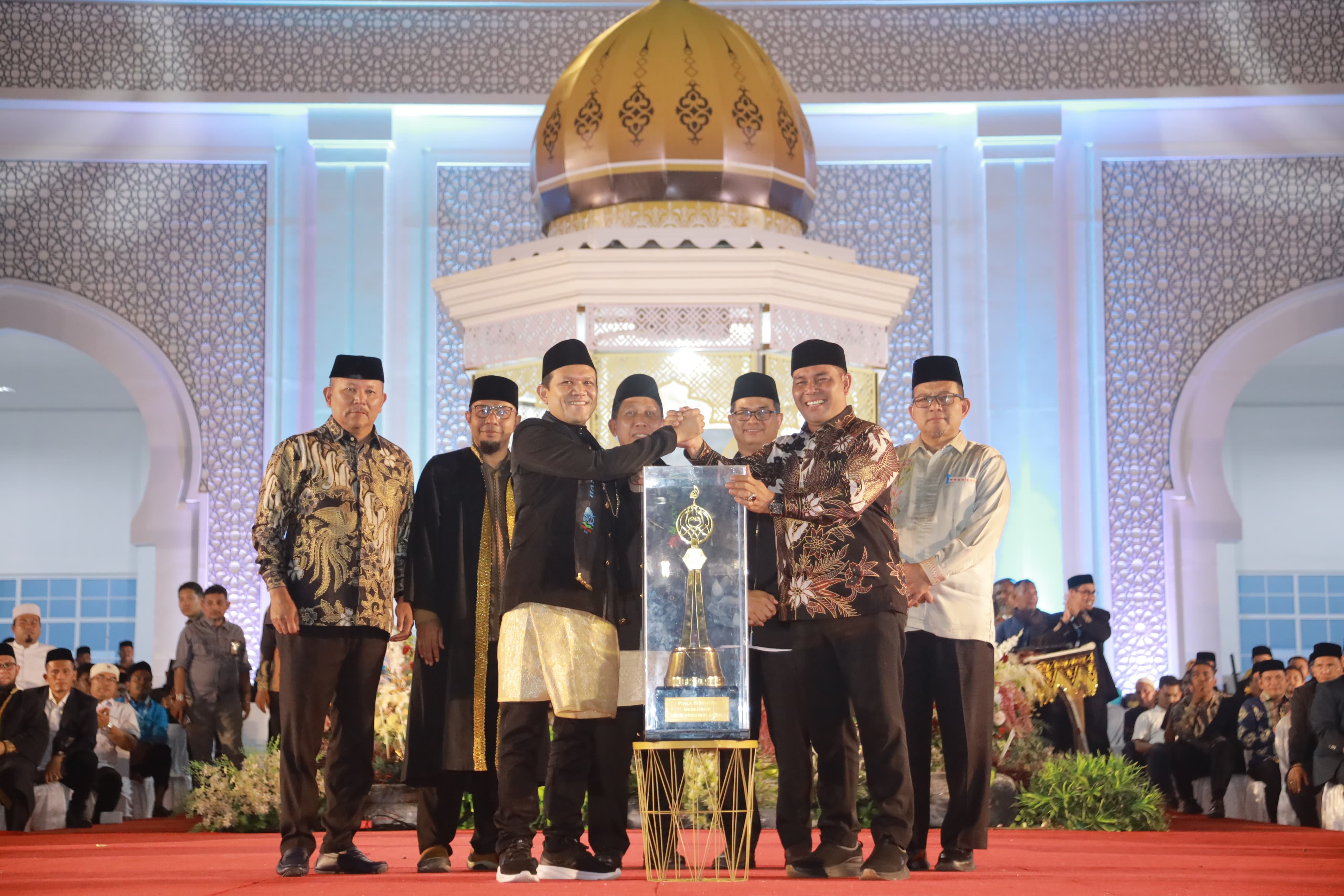 Bupati Aceh Besar H Muharram Idris (Syech Muharram) menerima piala bergilir juara umum MTQ ke-37 Aceh tahun 2025, dari Wakil Gubernur Aceh Fadhlullah SE, pada malam penutupan, di Arena Utama, Komplek Perkantoran Pemkab Pidie Jaya, Jumat (07/11/2025) malam.