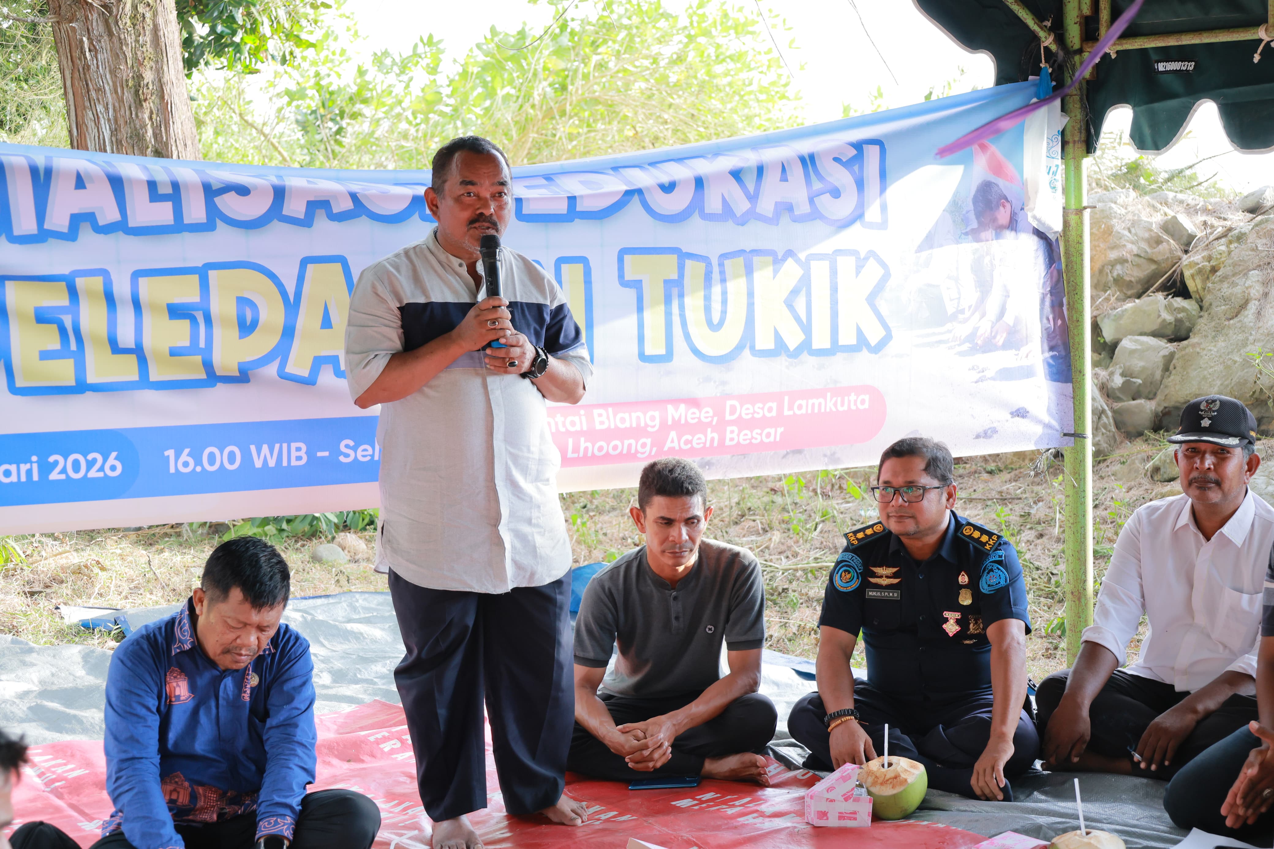 Asisten II Sekda Aceh Besar M Ali SSos MSi, menyampaikan sambutannya pada acara sosialisasi, edukasi dan pelepasan tukik (bibit penyu), di Pantai Blang Mee, Gampong Lamkuta, Kecamatan Lhoong, Kabupaten Aceh Besar, Jumat (30/01/2026).